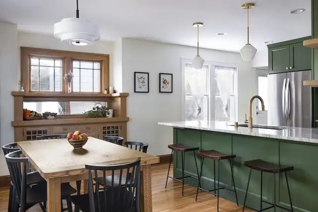 Craftsman kitchen with a dark green island, white quartz top, original wood built-in buffet and brass faucet