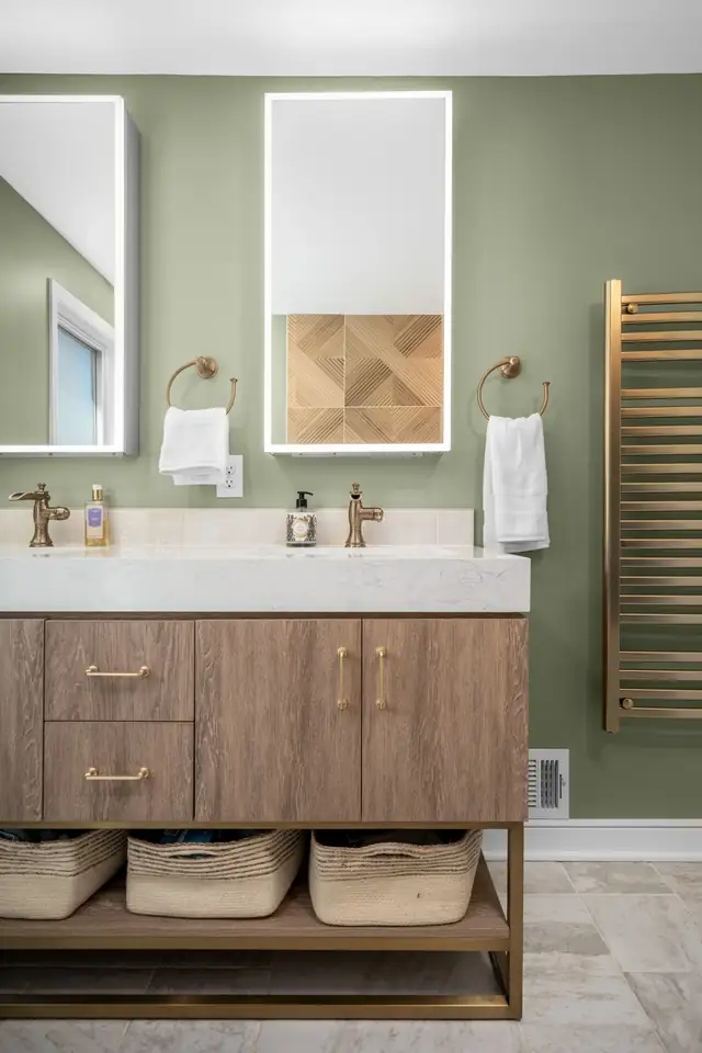 Lake Nokomis primary bathroom remodel with sage green walls, a floating wood double vanity, backlit mirrors and a brass towel warmer