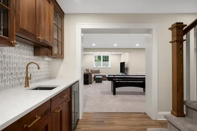 Montcalm lower level in St. Paul with a walnut wet bar, patterned backsplash and a game room beyond